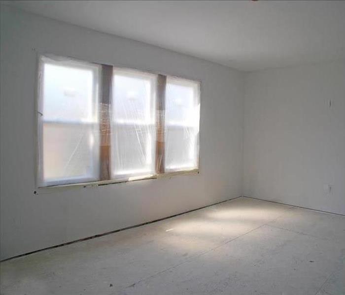 An empty office space with new windows still covered, fresh drywall, and bare floors.