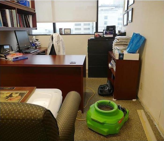 Interior shot of office with belongings and an industrial SERVPRO fan drying the room.
