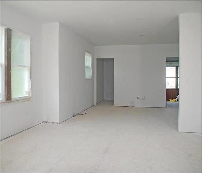 A completely empty kitchen with bare floors and drywalls. 