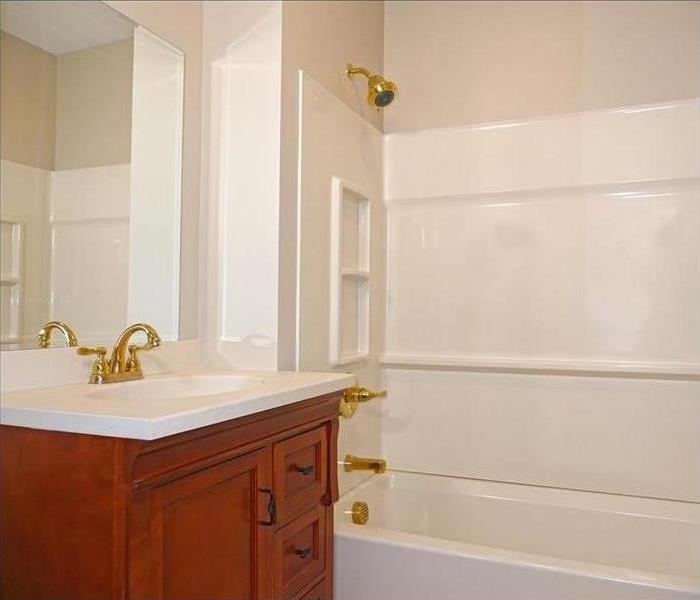 A bathroom completely remodeled with a nice new sink with cabinets and all brand new shower fixtures that match the sink.