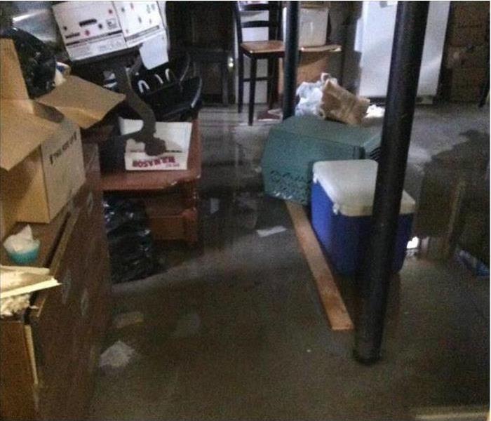 A basement that's been flooded with a fair amount of water and many belongings that are wet as well.