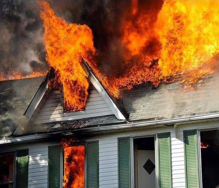 A house burns and flames shoot out windows.