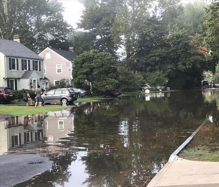 A street and homes are flooded with water from a burst sewer line