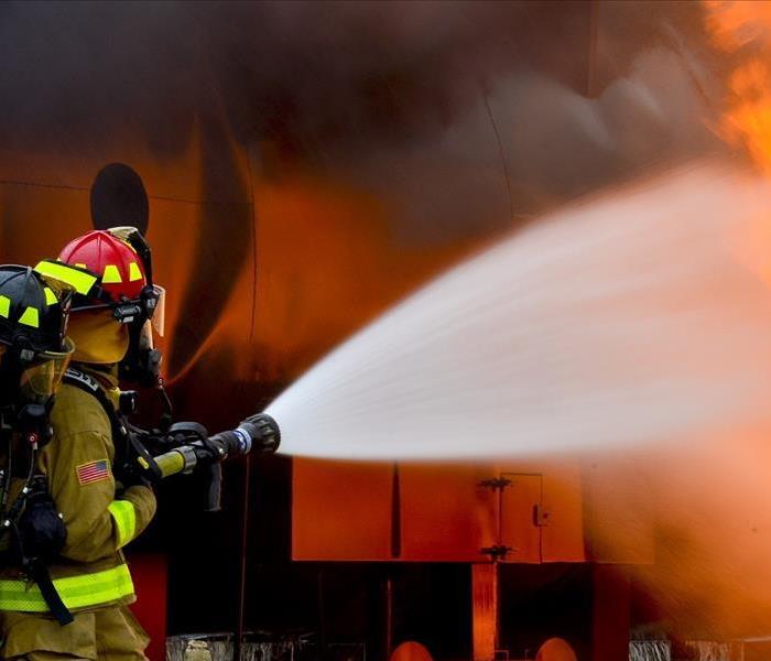 A firefighter puts water on a burning house