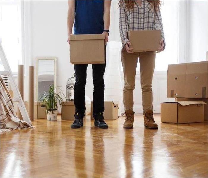 A man and woman stand among moving boxes